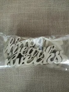 Detalle de accesorio hito de madera con recortes de palabras inglesas para foto de bebe.