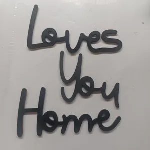 Vista di dettaglio della decorazione con lettere in legno nero Loves You Home per casa.