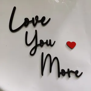 Vista dettagliata delle lettere in legno corsive nere Love You More con cuore rosso.