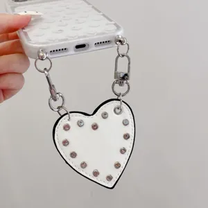 Gros plan sur la coque de téléphone transparente avec pendentif cœur et chaîne en métal.