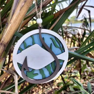 Detailed close up of wooden ocean fish pendant, featuring carved layered coastal hanging decor.