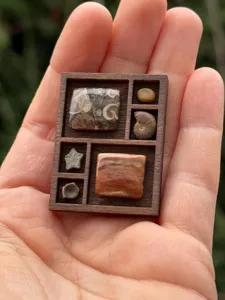 Nahaufnahme des hölzernen Miniatur-Schmuckregals mit kleinen fossilen Steinen im Detail.