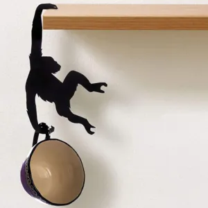 Gros plan du crochet de suspension en silhouette de singe créatif présentant une tasse.