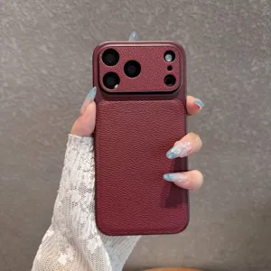 Detailed shot of wine red leather texture phone case held in hand, showing camera protection.