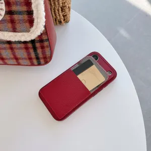 Close-up detail view of the red leather phone case with card slot on white table.