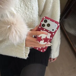 Detailed close-up view of a red and white polka dot phone case with a cute star phone grip.