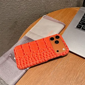 Gedetailleerd overzicht van het oranje krokodillenstructuur telefoonhoesje op houten tafel.