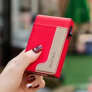 Close-up detail of a red leather and khaki card holder with metal pop-up mechanism.