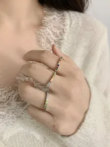 Detail shot of dainty rainbow zircon stacking rings worn on hand, elegant fashion jewelry.