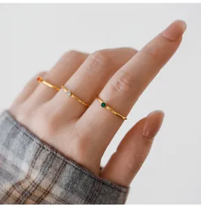 Primer plano de anillos finos dorados decorados con piedras de circonita coloridas.