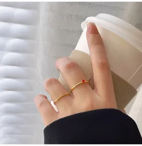 Conjunto de anillos de oro minimalistas delicados con circón rojo y detalle de banda texturizada.