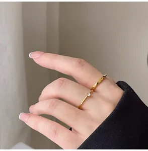 Detalle de anillos dorados minimalistas con circonita delicada y diseño geométrico facetado.