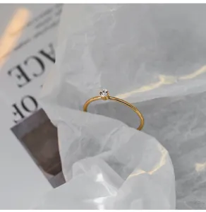 Vista detallada de anillo minimalista de acero titanio dorado con circonita brillante para mujer.