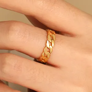 Gros plan détail d'une bague chaîne gourmette dorée élégante, beau porté au doigt.
