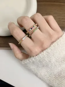 Close-up detail of dainty rainbow zirconia eternity rings, elegant stacked fashion jewelry.