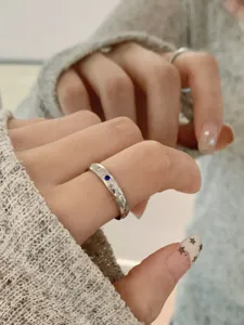 Anello minimalista in acciaio inossidabile con zirconi cubici e dettaglio di pietra blu.