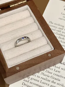 Anello elegante in acciaio al titanio con zirconi blu e bianchi, design geometrico.