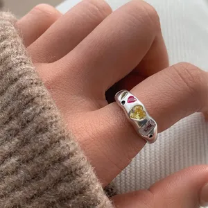 Gros plan détaillé montrant une bague tendance chunky en zircone colorée au doigt.