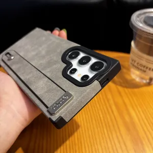 Vista detallada de funda de teléfono de ante vintage, con correa de muñeca y soporte.