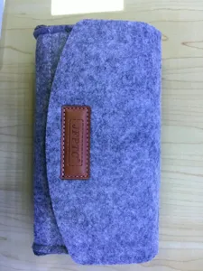 Detailed view of the grey felt phone pouch featuring a brown leather label and neat stitching.