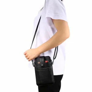 Close-up detail van de zwarte lederen telefoon crossbody tas gedragen door model met ritsvak.