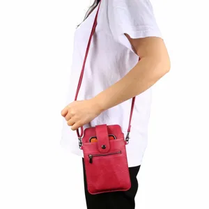 Detailopname van rode crossbody telefoontas gedragen met ritsvak en schouderband.