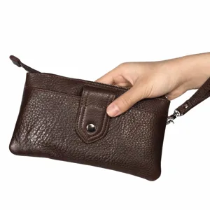Détail en gros plan d'un portefeuille pochette pour homme en cuir véritable avec dragonne et zip.