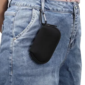 Detail shot of black neoprene earphone storage case hanging with metal carabiner on blue jeans.