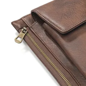 Gedetailleerd weergave van bruine lederen telefoonpouch met bronzen rits en flapsluiting.