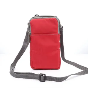 Red canvas phone cross-body bag detail, adjustable grey shoulder strap, zipper closure.