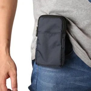 Close-up detail of a dark canvas phone waist bag with zipper pockets worn on clothing belt.