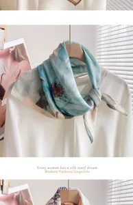 Vue détaillée du petit carré de foulard en coton lin floral bleu-vert élégamment noué au cintre.