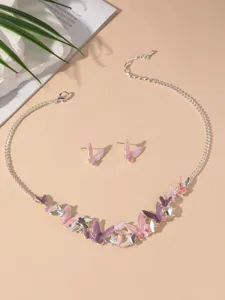 Detailed closeup view of the trendy silver butterfly necklace and matching pink stud earrings.