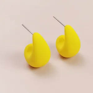 Close-up of bright yellow teardrop stud earrings, showing smooth minimalist geometric design.