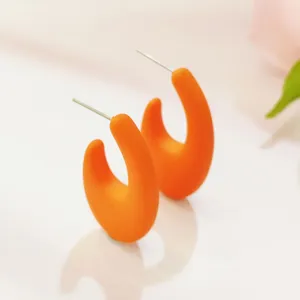 Nahaufnahme von halbrunden C-förmigen Ohrringen in leuchtendem matten Orange, süßer Stil.
