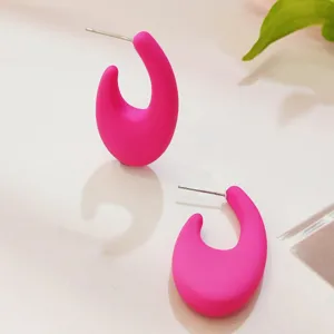 Nahaufnahme von hellen rosa Bonbon-C-förmigen Ohrringen mit glatter matter Oberfläche.