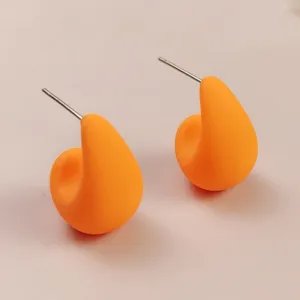 Detailed view of bright orange teardrop stud earrings, chic minimalist jewelry close-up.