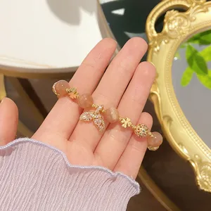 Close-up detail of orange moonstone beaded bracelet featuring a mermaid tail and gold clovers.