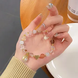 Close-up of natural crystal beaded bracelet featuring pearl ladybug and cute gold heart charms.