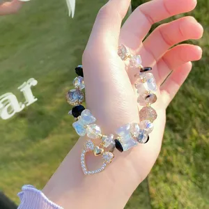 Closeup detail of sweet crystal glazed bead bracelet with bow heart charm, forest style jewelry.
