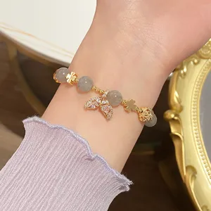Close-up of elegant gold mermaid tail bracelet with moonstone beads and clover charms.