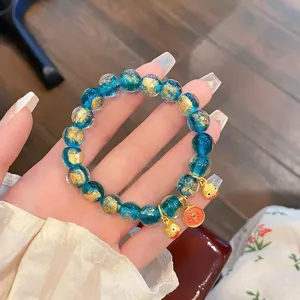 Vista dettagliata del bracciale di perle di vetro blu con foglia d'oro e graziosi ciondoli dorati.