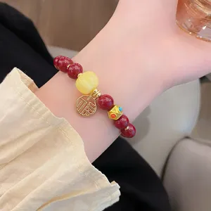 Gros plan de détail d'un bracelet de perles rouges de style chinois avec un pendentif chance.