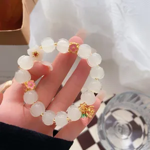 Squisito bracciale di perle di loto bianco con ciondoli floreali dolci e dettagli oro.