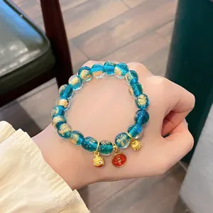 Primo piano del braccialetto di perle di vetro blu con foglia d'oro e mini ciondoli dettagliati.