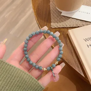 Gros plan détail du bracelet de perles en jade avec pendentif rose et style rétro élégant.