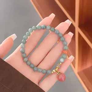 Joli bracelet en perles de jade de 6 mm avec pendentif pêche rose et détails dorés.
