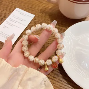 Primo piano dettagliato del bracciale di perle in vetro dorato in stile cinese con ciondoli.