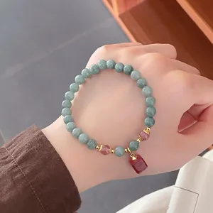 Vue detaillee du bracelet de perles en jade style retro chinois avec accents rouges et pendentif.