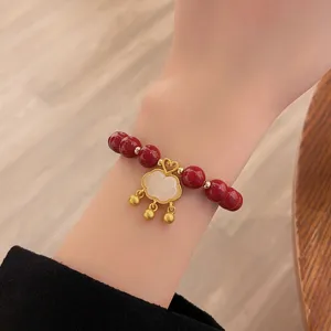Gros plan détail du bracelet de perles rouges chinoises avec fermoir Ruyi en or.